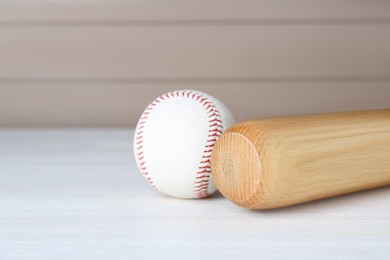 Photo of Baseball bat and ball on white wooden table, space for text. Sports equipment