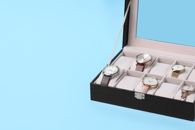 Photo of Jewelry box with many different wristwatches on light blue background, space for text