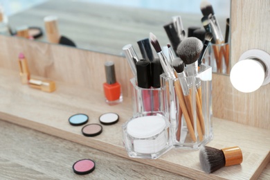 Organizer with cosmetic products for makeup on table near mirror