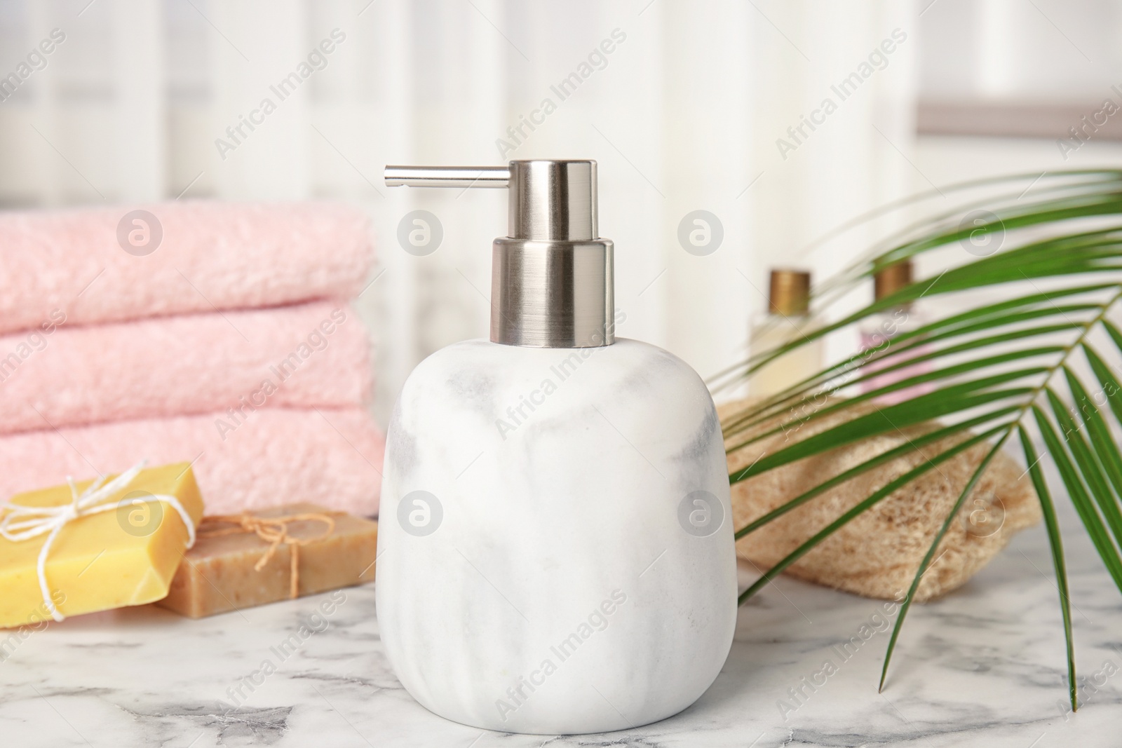 Photo of Marble dispenser, soap bars and luffa sponge on table