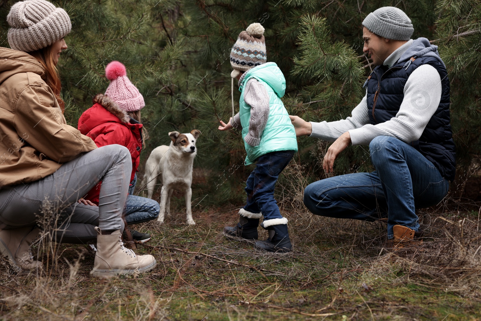 Photo of Happy family with dog spending time together in forest