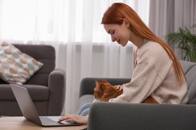 Photo of Happy woman stroking cat while working on sofa at home