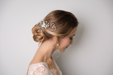 Photo of Young bride with elegant wedding hairstyle on light grey background