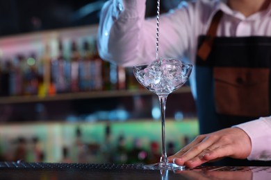 Photo of Bartender making fresh alcoholic cocktail at counter in bar, closeup. Space for text
