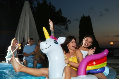 Photo of Group of happy people enjoying fun pool party in evening