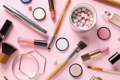 Flat lay composition with products for decorative makeup on pastel pink background