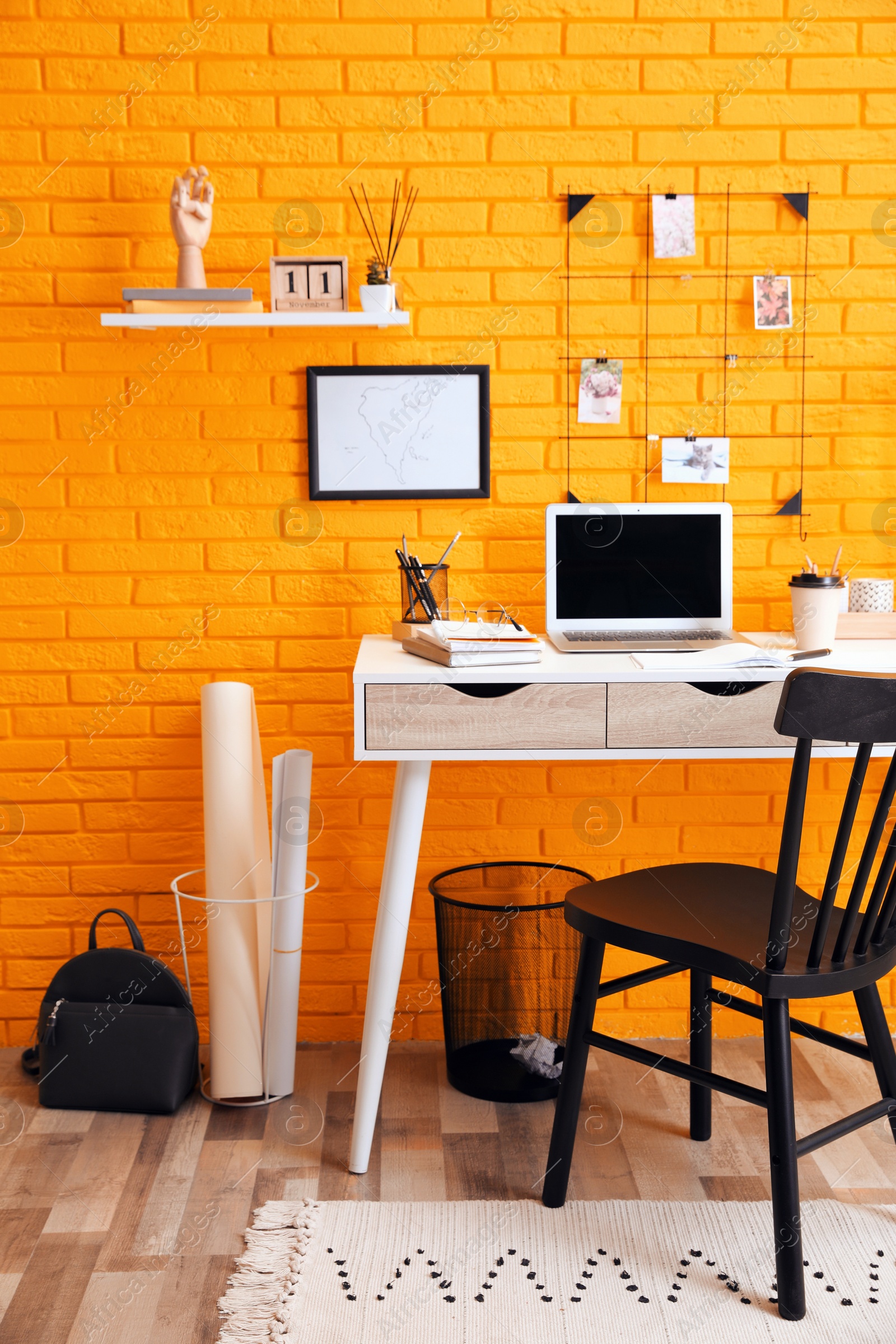 Image of Stylish home office interior with comfortable workplace near orange brick wall