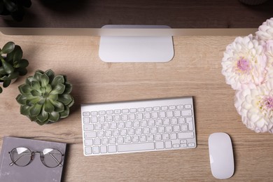 Modern computer, houseplants, flowers and glasses on wooden table, flat lay