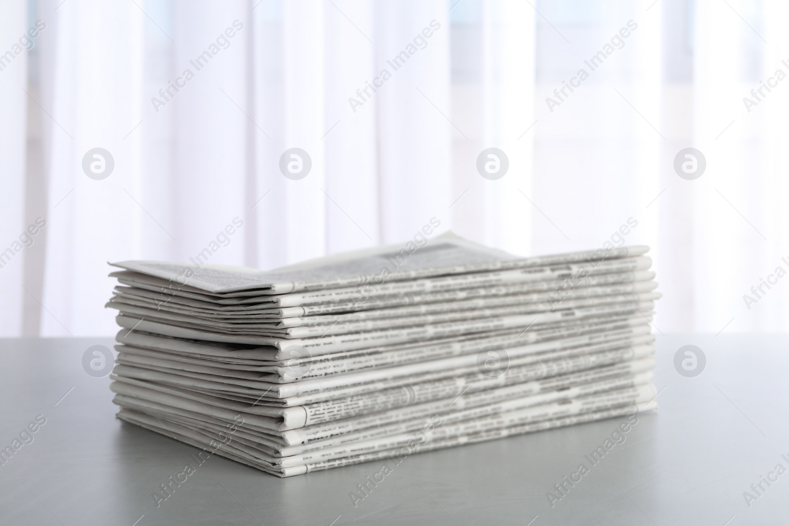 Photo of Stack of newspapers on light grey table. Journalist's work