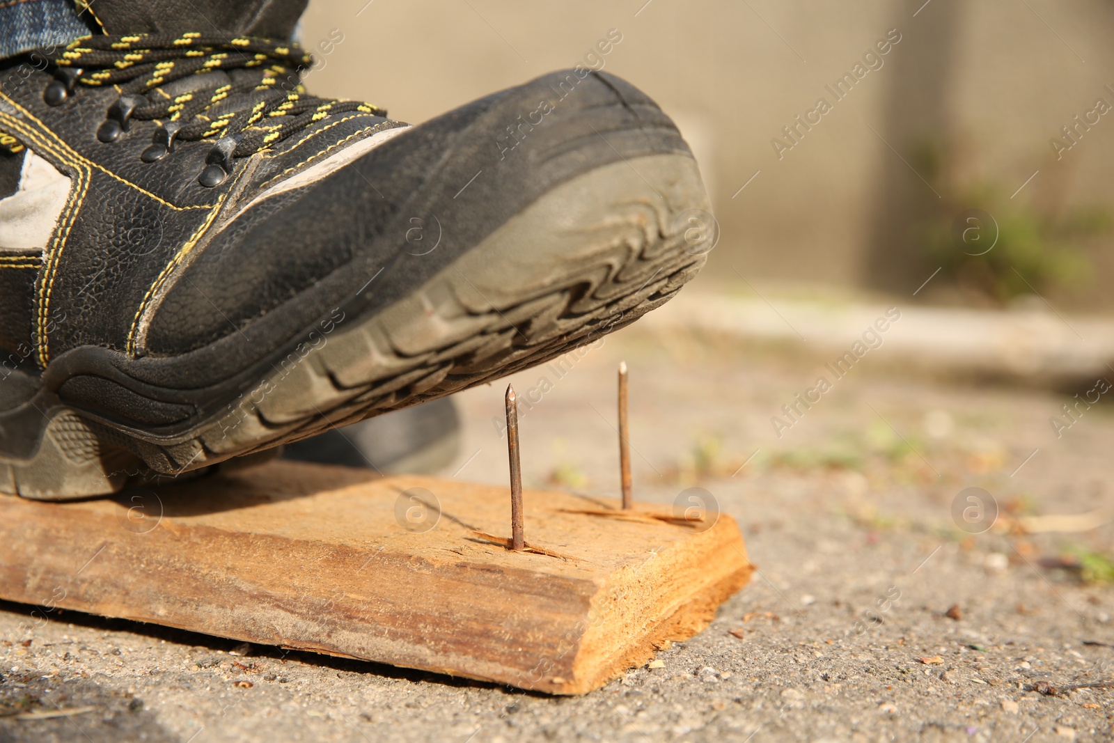 Photo of Careless worker stepping on nails in wooden plank outdoors, closeup. Space for text