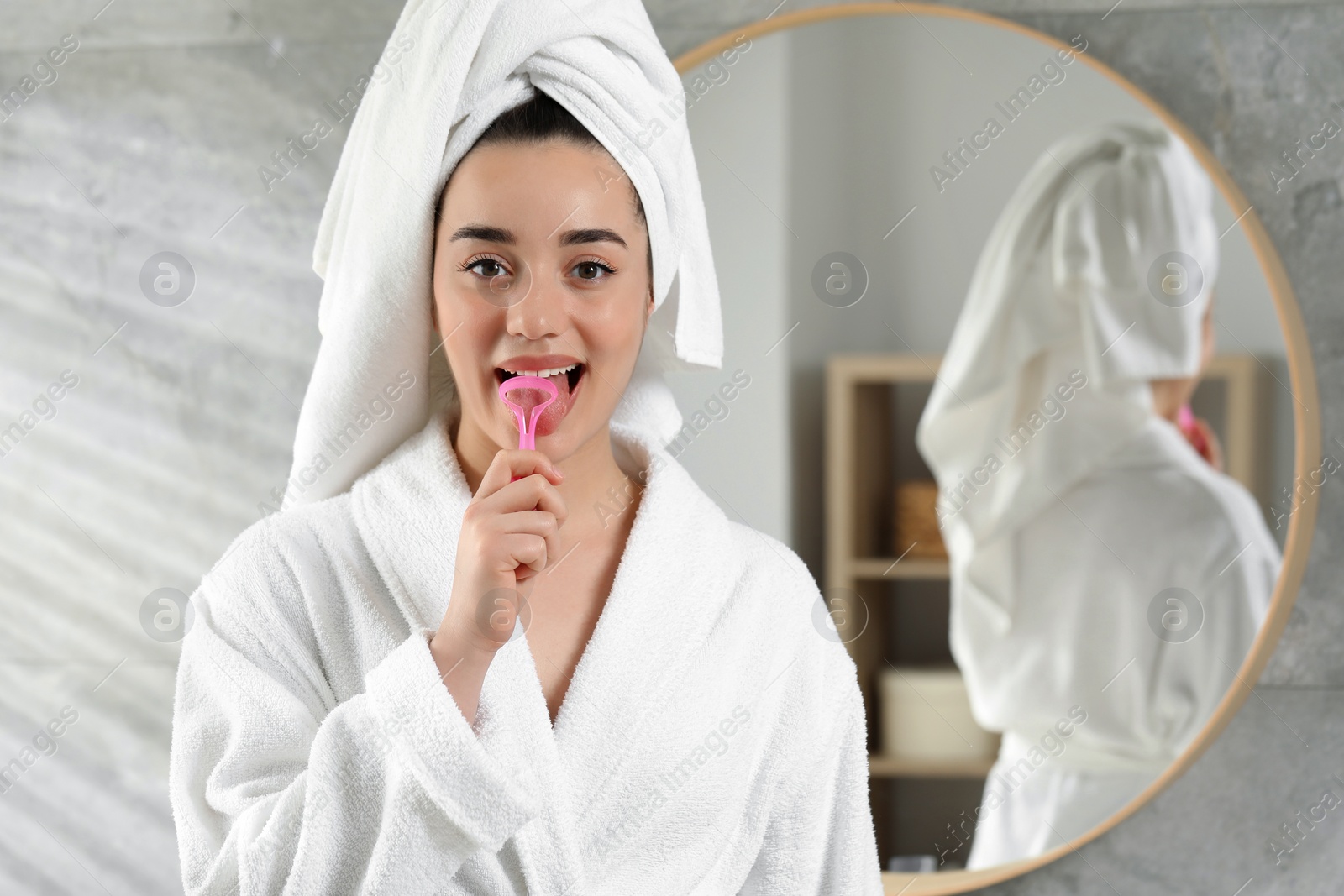 Photo of Happy woman brushing her tongue with cleaner in bathroom, space for text