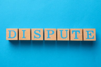 Photo of Word Dispute made with wooden cubes on light blue background, top view