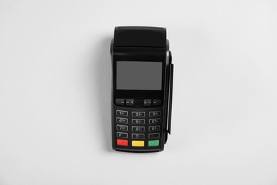 Modern payment terminal with credit card on grey background, top view