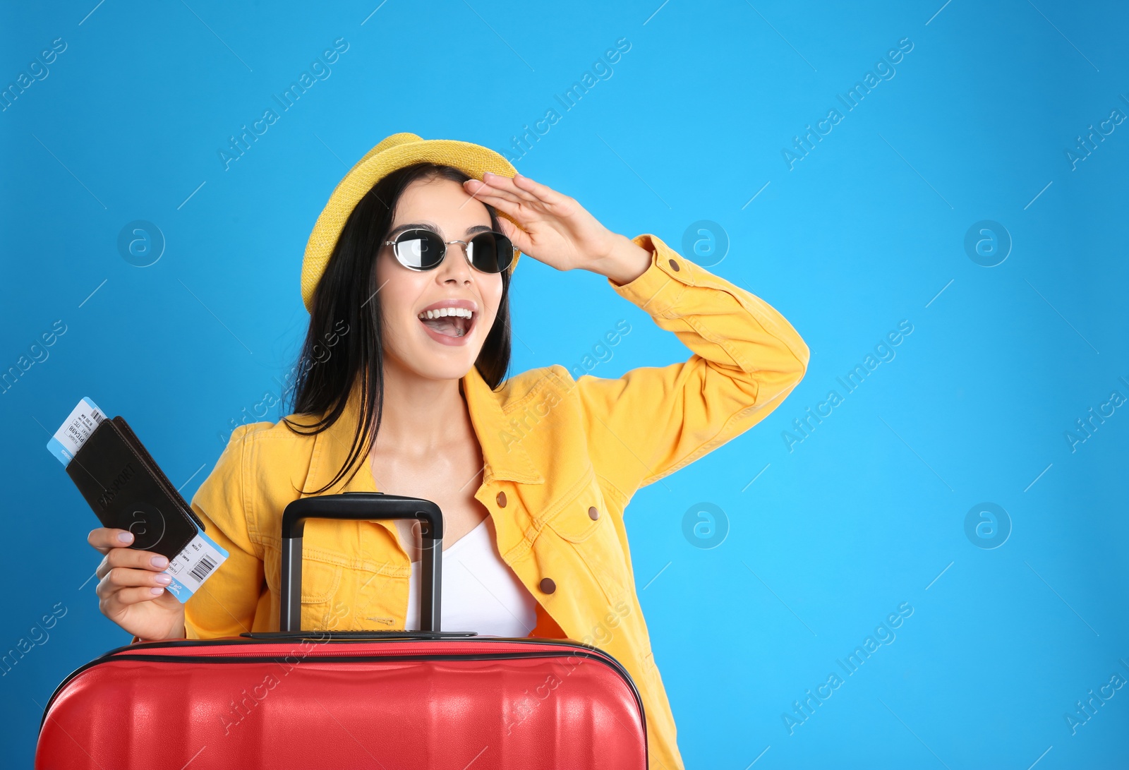 Photo of Beautiful woman with suitcase and ticket in passport for summer trip on blue background. Vacation travel