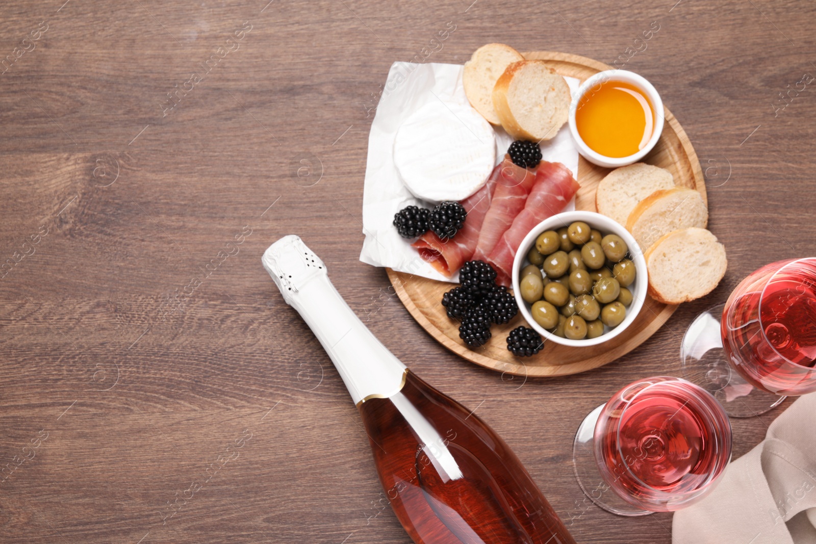 Photo of Delicious rose wine and snacks on wooden table, flat lay. Space for text