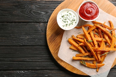 Board with sweet potato fries on wooden background, top view. Space for text