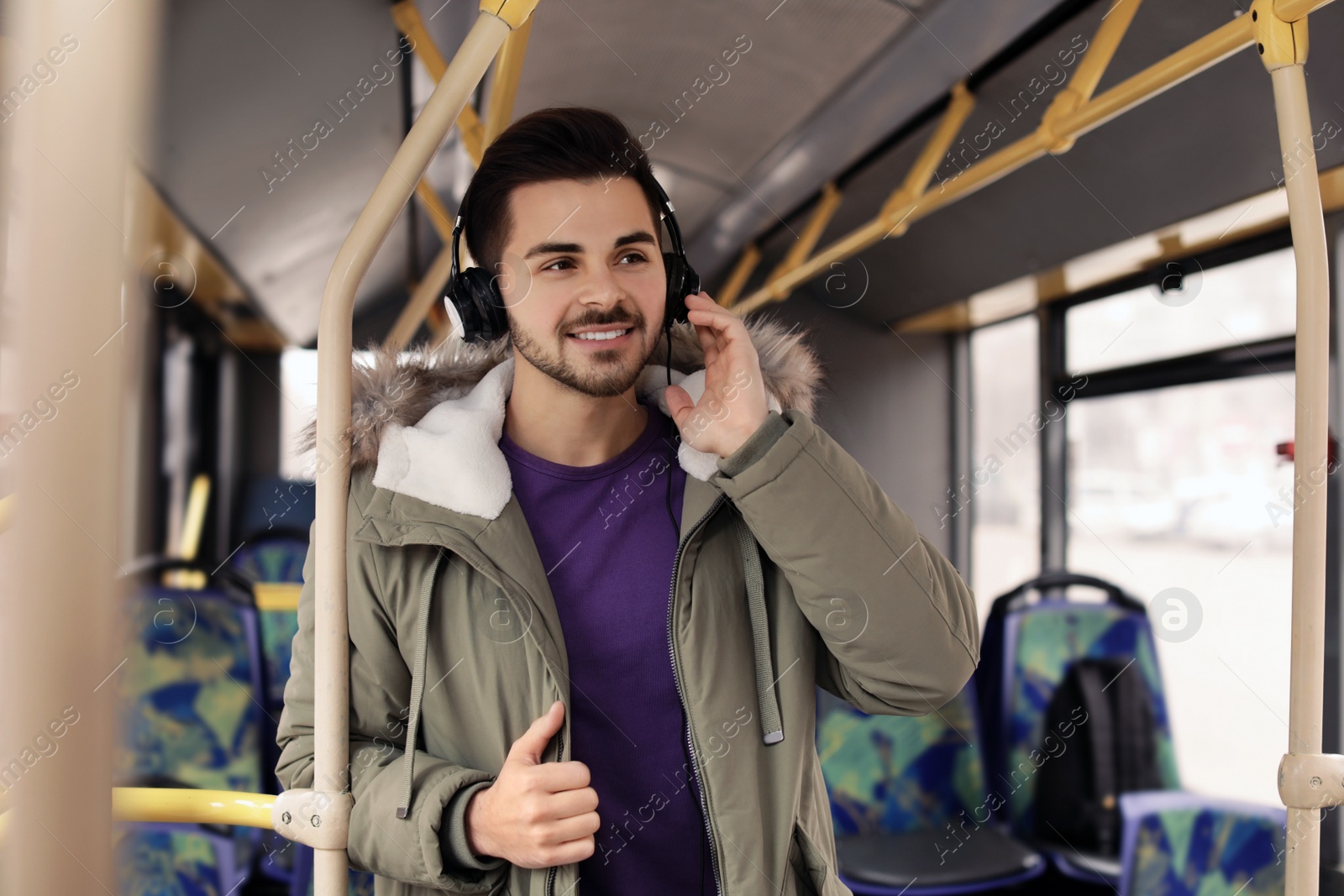 Photo of Young man listening to music with headphones in public transport