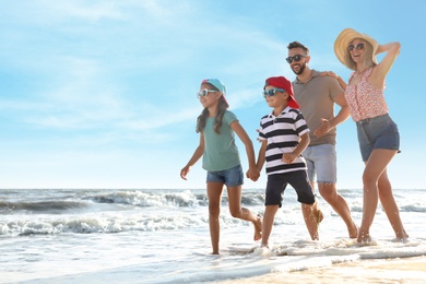 Happy family running on sandy beach near sea