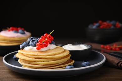 Photo of Tasty pancakes with natural yogurt, blueberries and red currants on wooden table. Space for text