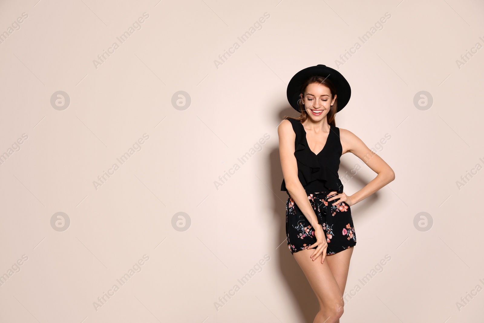 Photo of Young woman wearing floral print shorts and stylish hat on beige background. Space for text