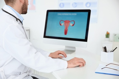 Photo of Young doctor working with computer in hospital. Gynecology department
