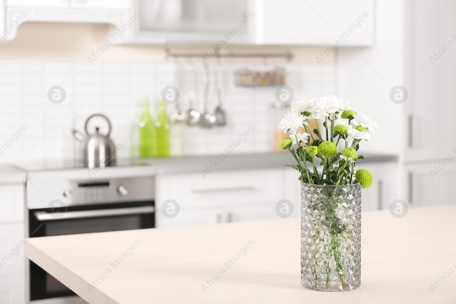 Photo of Vase with beautiful flowers on table in kitchen interior. Space for text