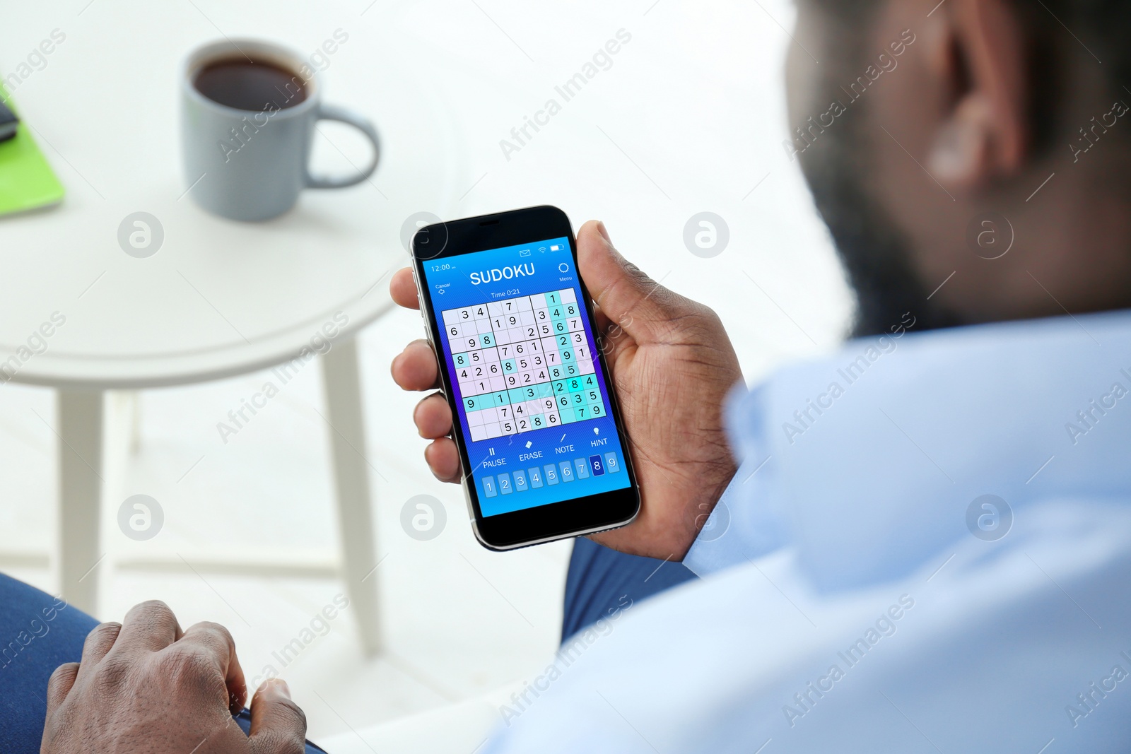 Image of Man playing sudoku game on smartphone indoors, closeup