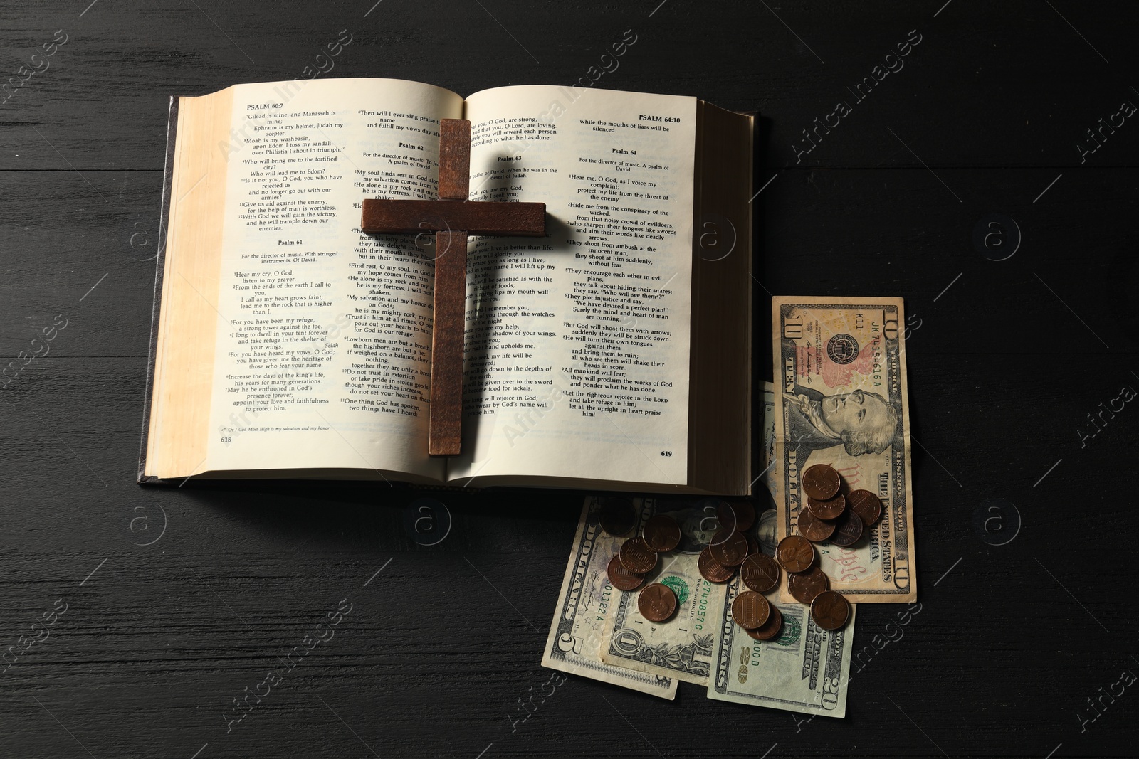 Photo of Donate and give concept. Coins, dollar banknotes, cross and Bible on black wooden table, flat lay