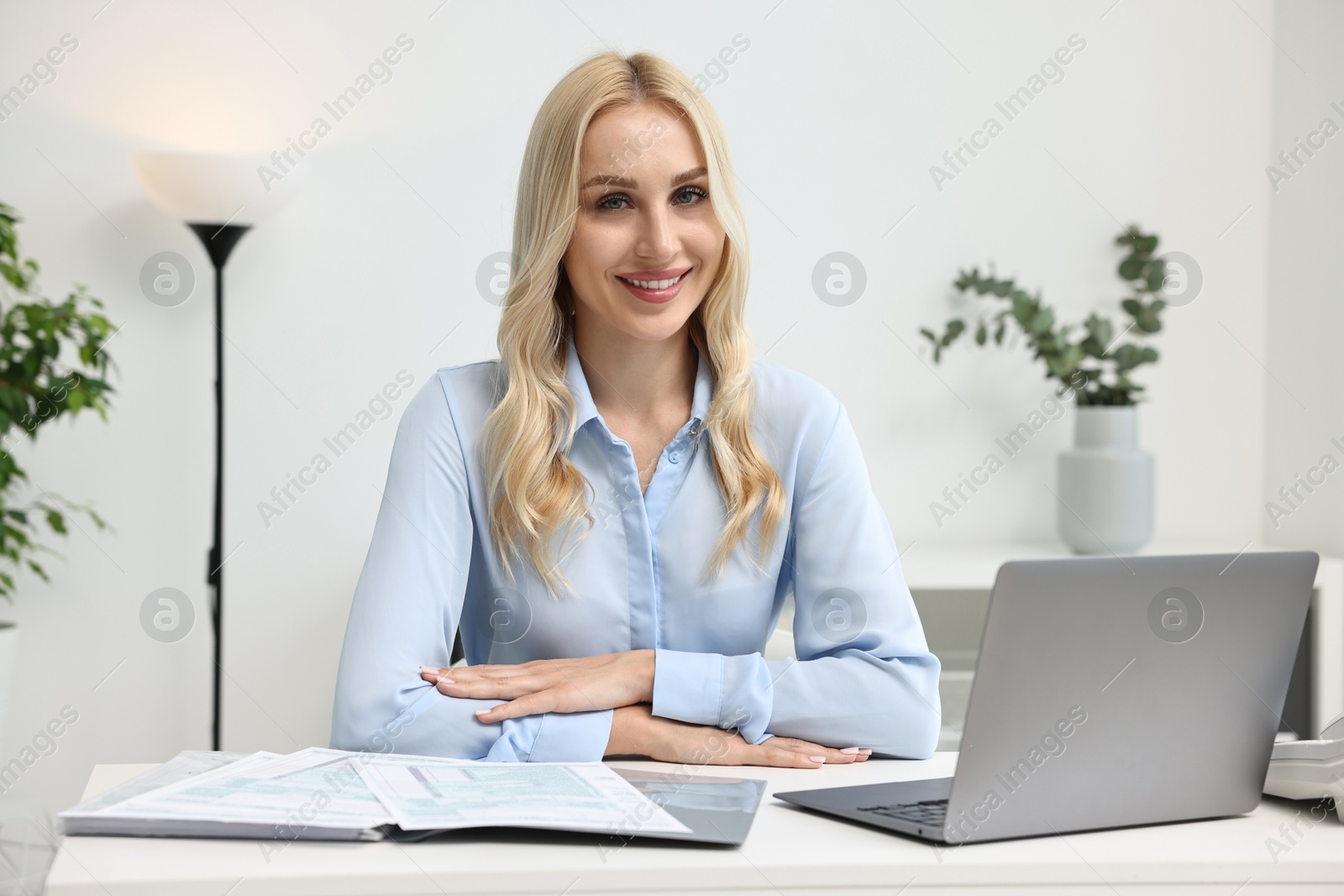 Photo of Happy secretary at table with laptop in office