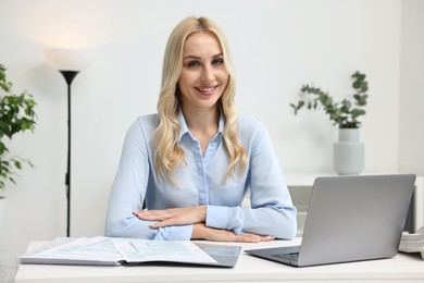 Happy secretary at table with laptop in office