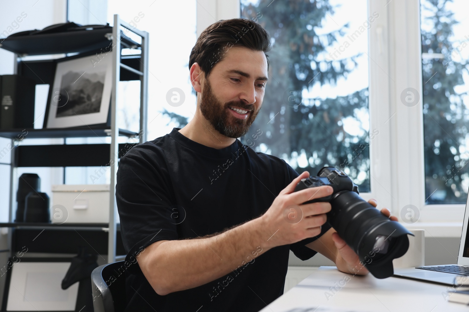 Photo of Professional photographer with digital camera at table in office