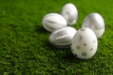 Traditional painted Easter eggs on green lawn, space for text