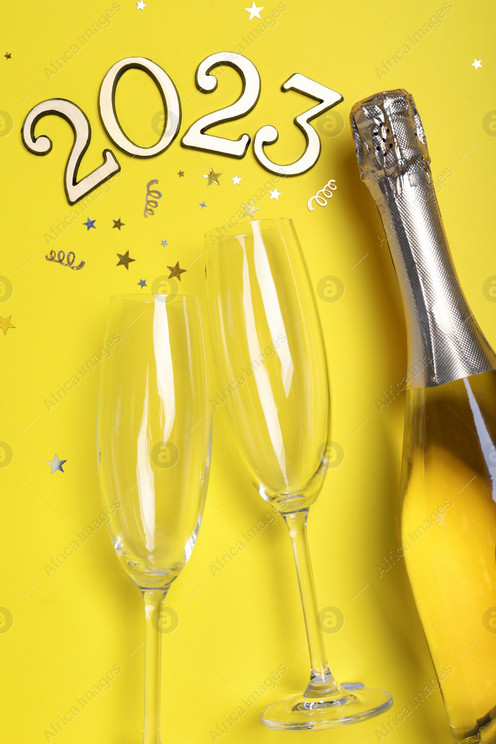 Photo of Happy New Year 2023! Flat lay composition with bottle of sparkling wine on yellow background