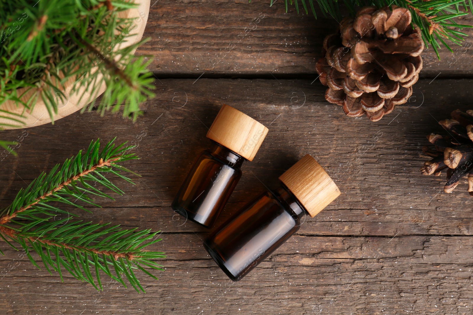 Bottles of pine essential oil, conifer tree branches and cones on wooden table, flat lay Photo of Bottles of pine essential oil, conifer tree branches and cones on wooden table, flat lay