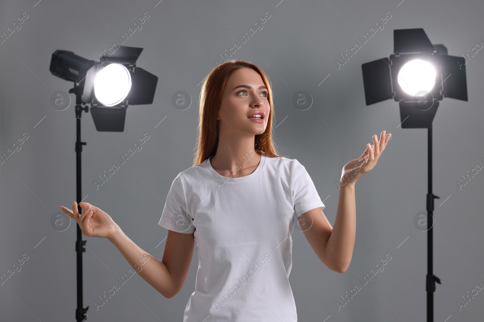 Photo of Casting call. Emotional woman performing on grey background in studio