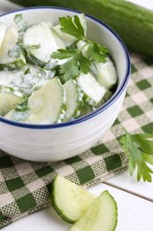 Delicious cucumber salad in bowl on white table