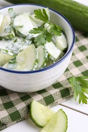 Photo of Delicious cucumber salad in bowl on white table