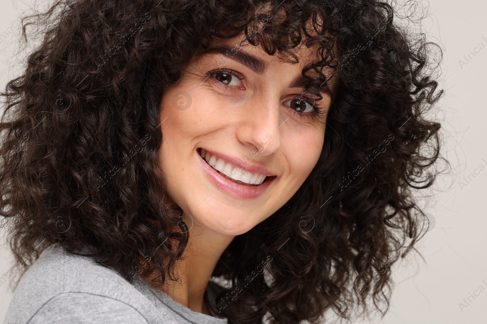 Photo of Young woman using teeth whitening strip on light grey background