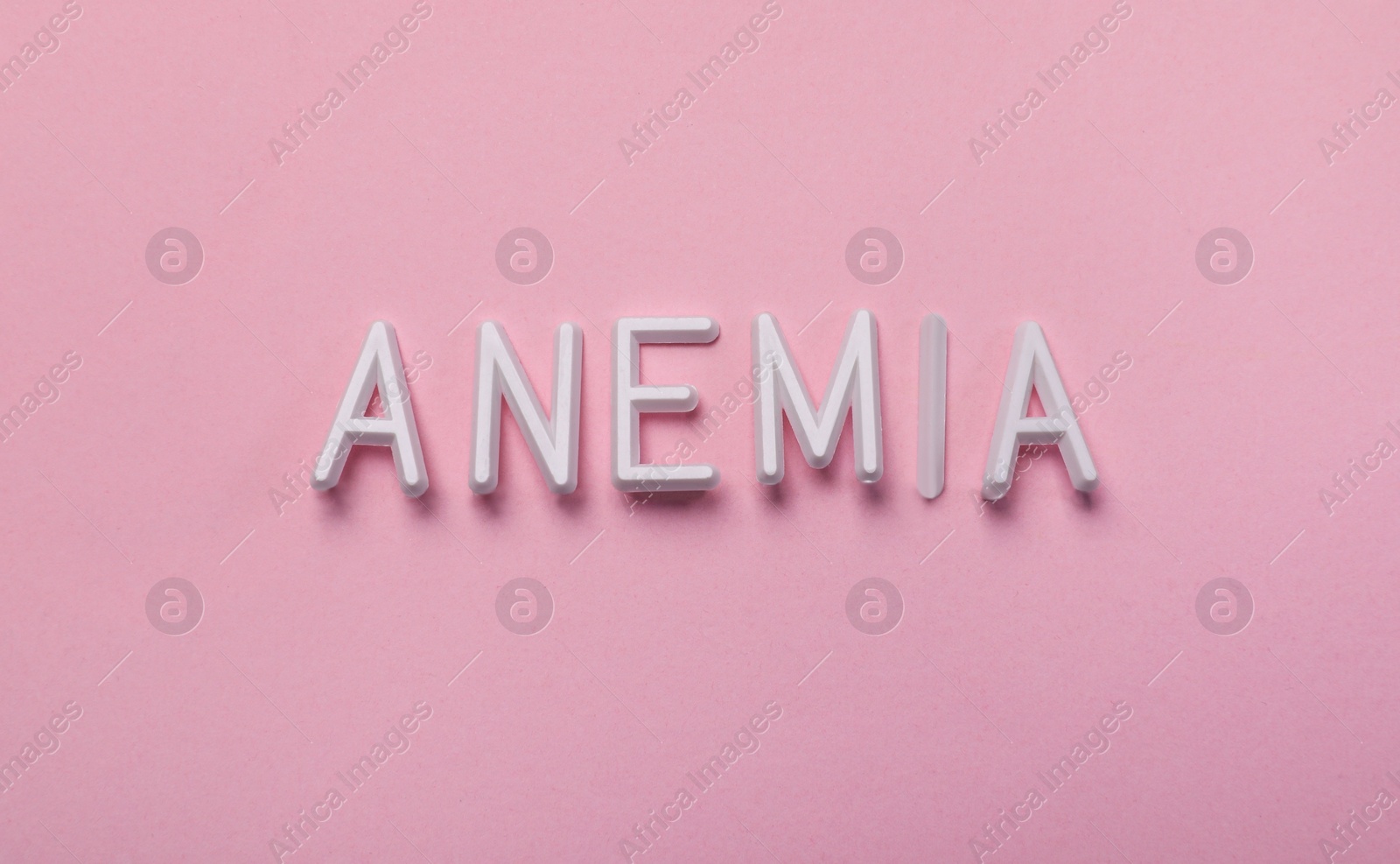 Photo of Word Anemia made with white letters on pink background, flat lay