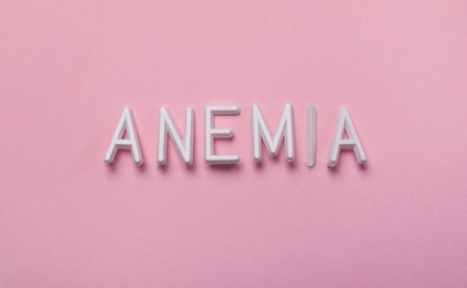 Photo of Word Anemia made with white letters on pink background, flat lay