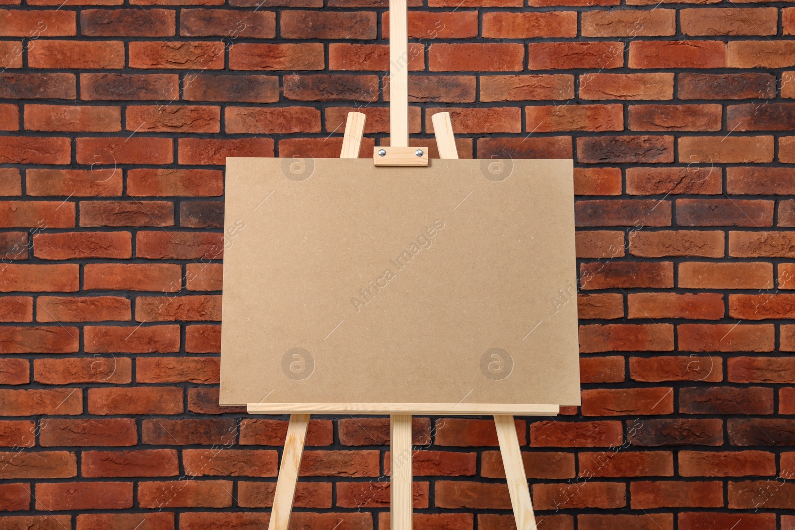 Photo of Wooden easel with blank board near brick wall