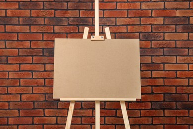 Photo of Wooden easel with blank board near brick wall