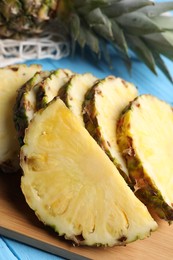Photo of Slices of ripe juicy pineapple on light blue wooden table, closeup