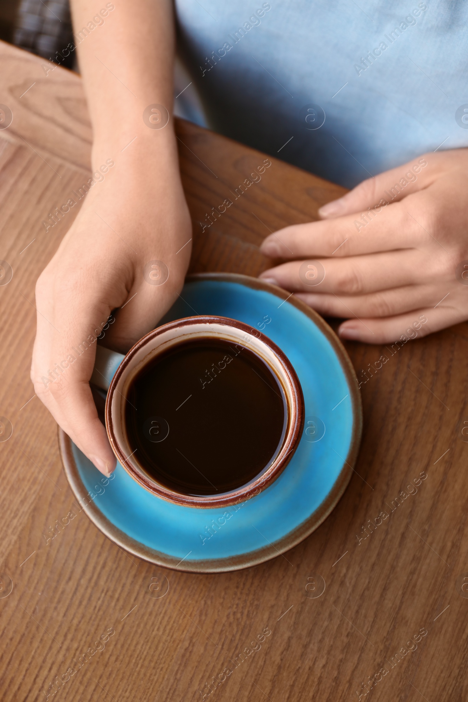 Photo of Woman with cup of fresh aromatic coffee at table, top view