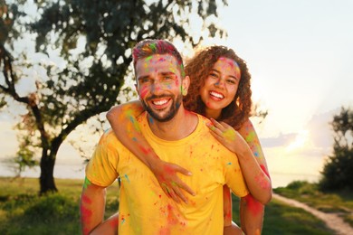 Happy couple covered with colorful powder dyes outdoors. Holi festival celebration