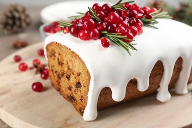 Photo of Traditional classic Christmas cake decorated with cranberries, pomegranate seeds and rosemary on board, closeup