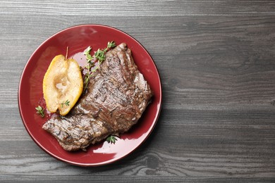 Delicious roasted beef meat, caramelized pear and thyme on grey wooden table, top view. Space for text