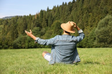 Photo of Feeling freedom. Man enjoying nature on green grass outdoors, back view