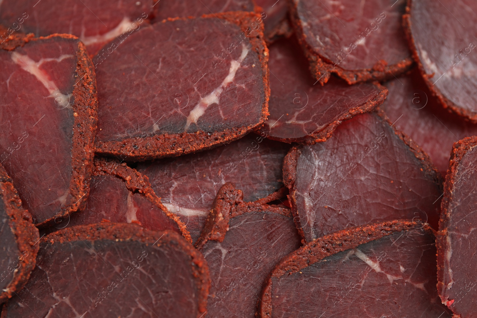 Photo of Delicious dry-cured beef basturma slices as background, top view