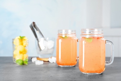 Photo of Mason jars with tasty melon drink on table